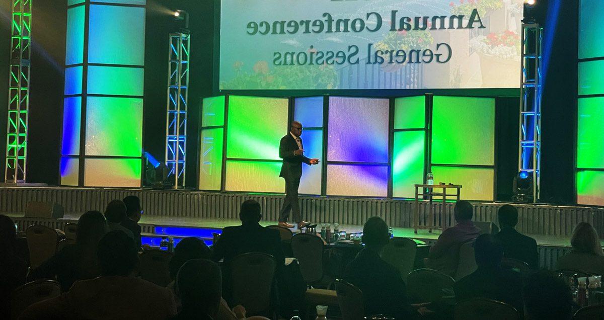 Speaker in front of an audience in an auditorium with the words, 